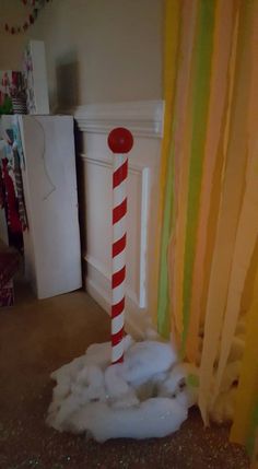 a red and white candy cane sticking out of the ground in front of a curtain