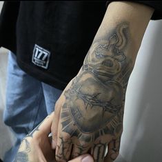 a man with a tattoo on his arm holding onto a hand that has a heart and cross tattooed on it