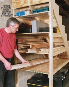 a man standing in front of a shelf filled with wooden planks and plywood