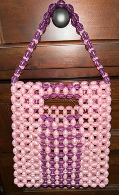 a pink and purple beaded purse hanging on a dresser