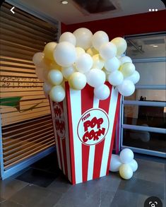 a popcorn box filled with white balloons sitting on top of a floor