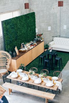 a table set up with plates and bowls on it in front of a green wall