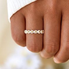 a woman's hand wearing a gold ring with daisies on the middle finger