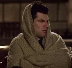 a man in a sweater and tie is wrapped up with a blanket over his head