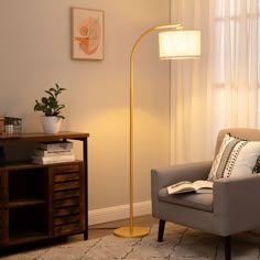 a living room with a chair, lamp and books on the table next to it