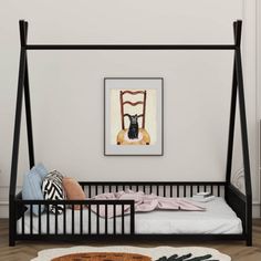 a black metal bed frame with a cat sitting on it's head in front of a white wall