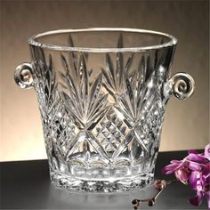 a glass vase sitting on top of a table next to a purple flower