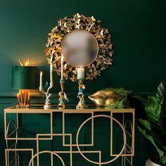 a table with candles and decorations on it in front of a mirror, potted plant