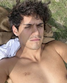 a shirtless man laying in the grass with his eyes closed and head turned to the side