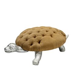 a turtle shaped ottoman sitting on top of a white floor next to a metal object