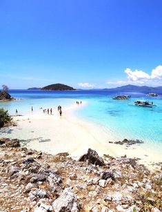 people are standing on the beach in clear blue water