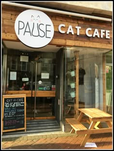 the outside of a cat cafe with wooden benches and tables in front of it's glass doors