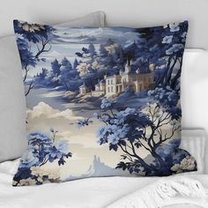 a blue and white pillow sitting on top of a bed next to pillows with trees