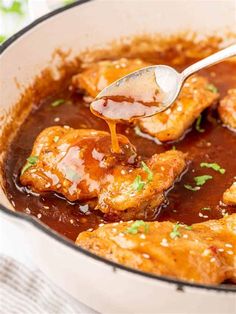 a spoon is pouring sauce on chicken wings in a skillet with brown gravy