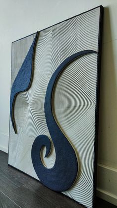 an abstract painting on the wall with blue and white swirls in front of it