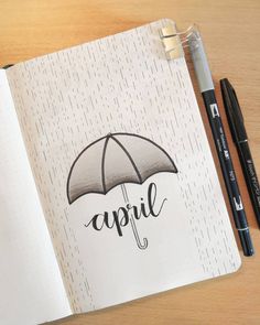 an open notebook with the word april written on it and an umbrella drawn in black ink