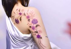 the back of a woman's shoulder with purple flowers on her left arm and chest