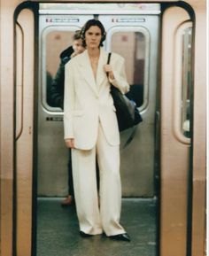 a woman in a white suit is standing on the subway