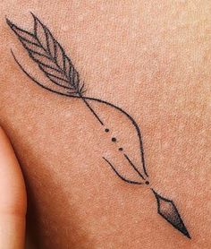 a tattoo on the back of a woman's shoulder with a feather and arrow