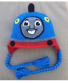 a crocheted blue and red hat with a smiling thomas the train on it