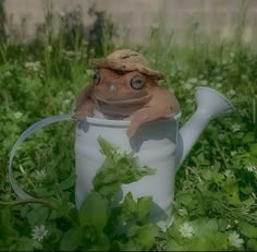 a frog is sitting in a watering can