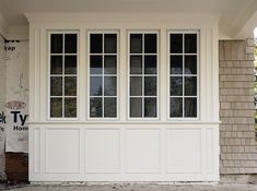 a white house with three windows on the front and one window in the back side