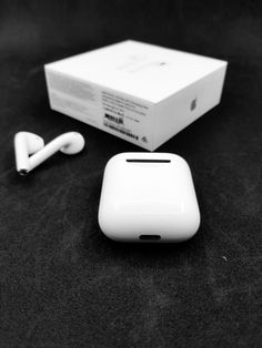 an apple airpods sitting on top of a black surface next to a white box