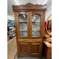 a wooden china cabinet with glass doors in a store