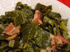 a white plate topped with collard greens and bacon on top of it's side