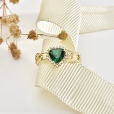 The love in your heart will sparkle with this one-of-a-kind emerald heart ring. Crafted from gleaming 14K yellow gold and set with a striking emerald gemstone cut into an intricate heart shape, this ring is a declaration of affection that will last forever. The emerald heart centerpiece catches the light from every angle, glowing a vivid green that symbolizes vitality, passion and eternal spring. Two sculpted gold bands intertwine below the emerald in a graceful heart shape, representing two souls joining together. Surprise the special woman in your life with this heartfelt gift and watch her eyes light up each time she glances down at this meaningful ring. This ring is the perfect romantic gift for a birthday, Valentine's Day or just because. Treat yourself or a loved one to a uniquely pe Green Fine Jewelry Heart Ring For Wedding, Elegant Heart Ring With May Birthstone Gemstone, Elegant May Birthstone Heart Ring With Gemstone, Green Heart Ring For May Birthstone, Fine Jewelry Style, Fine Jewelry Green Heart Ring For May Birthstone, Green Heart Ring For May Birthstone, Elegant Green Heart Promise Ring, Elegant Heart Ring For May Birthstone Gift, Elegant Heart Shaped Emerald Ring For May Birthstone