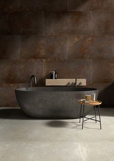 a bath tub sitting on top of a floor next to a wooden table and stool