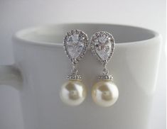 Classic cubic zirconia and pearl bridal earrings in rhodium plated brass setting. Earrings feature clear cubic zirconia teardrop ear post and a 10mm Swarovski cream pearl dangle drop. Total length of the earrings is 2.7 cms.For matching necklace click:https://www.etsy.com/listing/252977878/cream-pearl-and-crystal-bridal-necklace?ref=shop_home_active_10For matching bracelet click:https://www.etsy.com/listing/253699301/classic-bridal-cream-pearl-bracelet?ref=shop_home_active_5 To browse my collect Silver Pearl Drop Bridal Earrings For Anniversary, Diamond White Cubic Zirconia Pearl Earrings For Wedding, Anniversary Silver Bridal Earrings With Pearl Drop, Classic Cubic Zirconia Pearl Earrings For Wedding, Classic Pearl Earrings With Cubic Zirconia For Wedding, Silver Pear-shaped Bridal Earrings For Anniversary, Silver Classic Pearl Earrings For Mother Of The Bride, Classic Silver Pearl Earrings For Mother Of The Bride, Wedding Cubic Zirconia Round Pearl Earrings