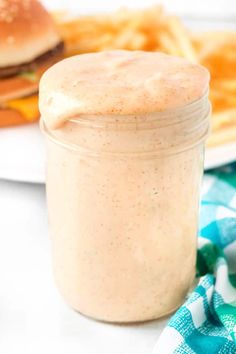 a close up of a jar of food on a table next to a plate with fries