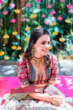 a woman sitting on top of a pink bench in front of flowers and hanging decorations