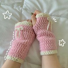 a person wearing pink crocheted mitts on top of a bed