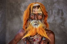 an old man with orange hair and beard wearing chains around his neck is looking at the camera