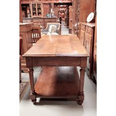 a wooden table sitting in the middle of a room next to chairs and other furniture