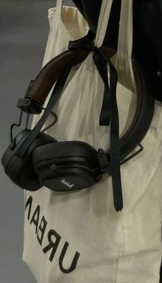 a white bag with black headphones on the handle and straps hanging from it's side