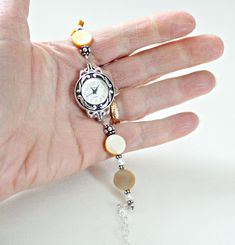 "Mother of pearl sterling silver bracelet watch is handcrafted. Would make a great 50th birthday gift for Mom or Mothers Day gift from son or daughter! Beige shell mother of pearl showcased with white freshwater pearls and Bali sterling silver. Watch is adjustable from 6 1/4\" to 8 1/2\". Metaphysical meaning of Mother of Pearl: Mother of Pearl, considered a protection stone, is a stress relieving stone; relaxing, soothing and calming to the emotions. It stimulates our intuition, imagination, se Timeless Round Pearl Bracelet As Gift, Elegant Nickel-free Watches As Gifts, Silver Jewelry And Watches With Bracelet Strap As Gift, Vintage Silver Pearl Bracelet Gift, Silver Bracelet Strap Jewelry For Anniversary, Silver Strap Bracelet For Anniversary, Silver Pearl Jubilee Bracelet For Anniversary, Silver Jubilee Bracelet As A Gift, Handmade Round Pearl Bracelet For Anniversary