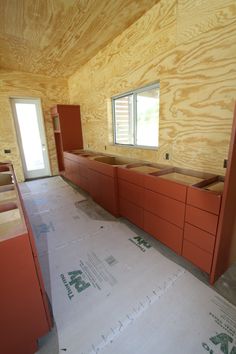 an unfinished room with red cabinets in it