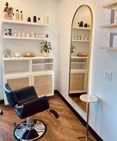 a salon chair sitting in front of a mirror and shelf with bottles on top of it