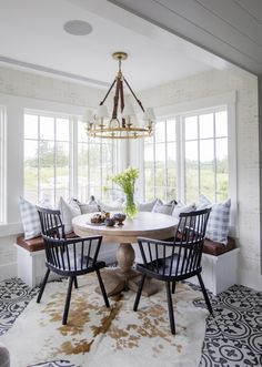 a dining room table with four chairs and a chandelier hanging from the ceiling