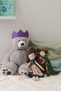 three stuffed animals sitting on top of a bed next to each other in a room