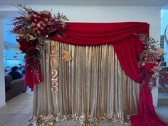 a red and gold stage set up for a wedding ceremony with flowers on the side