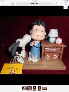 a figurine of a man kissing a dog next to a desk with a clock