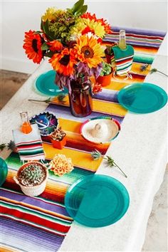 the table is set with colorful flowers and plates