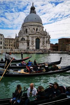 several gondolas with people sitting in them floating on the water near a building