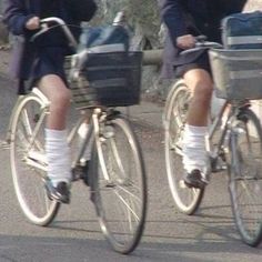 two people riding bikes with baskets on the back