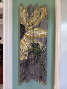 a piece of wood that has been painted with dragonflies on it and is hanging on the wall