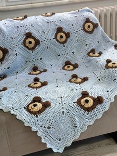 a crocheted blanket with teddy bears on it is sitting on a bench next to a radiator